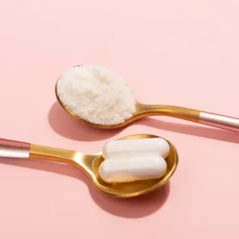 One spoon of collagen powder and two collagen capsules on the spoon